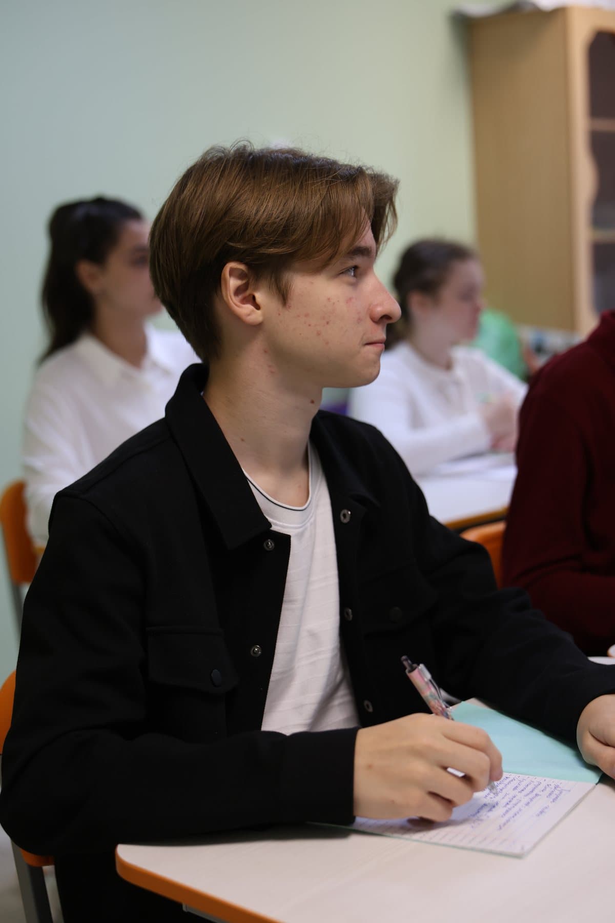 Старшеклассник пишет конспект на уроке